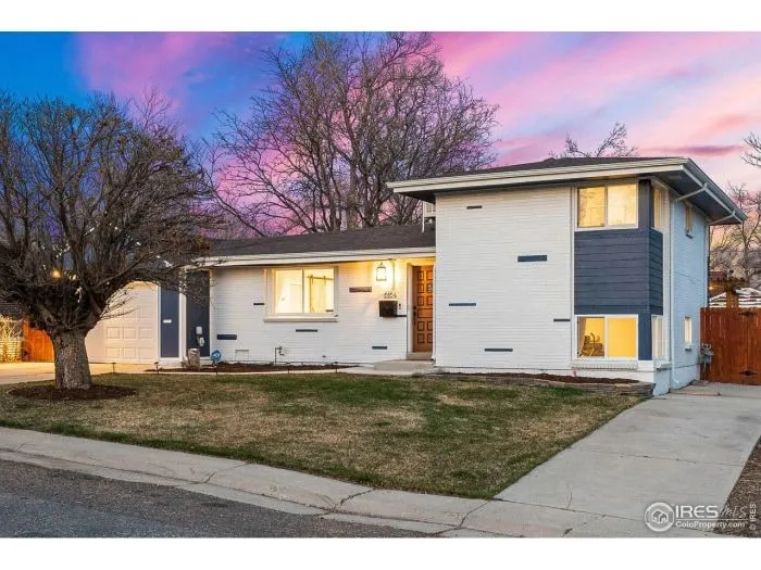 Mid-century home exterior at dusk under a pink sky