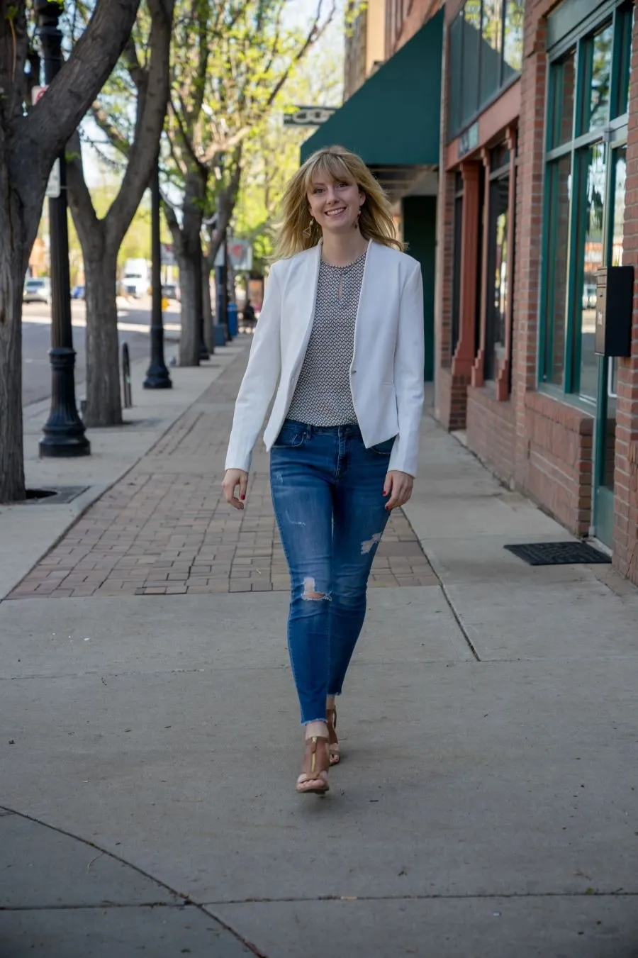 Hannah Hester walking along a tree-lined downtown sidewalk
